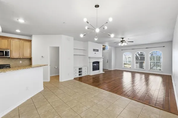 a large kitchen with kitchen island granite countertop a refrigerator a stove a sink and white cabinets with wooden floor