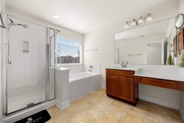 a spacious bathroom with a tub sink shower and mirror