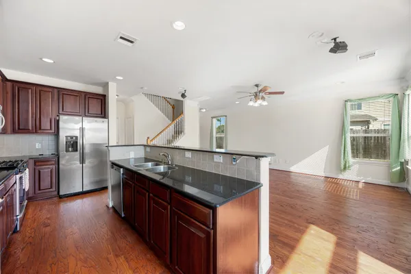 a kitchen with stainless steel appliances granite countertop a sink a stove and refrigerator