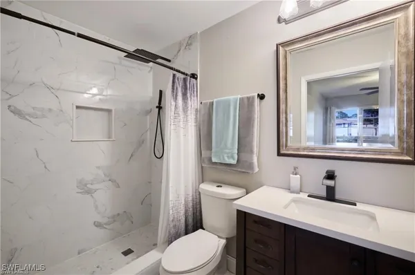 a bathroom with a sink vanity granite toilet and shower