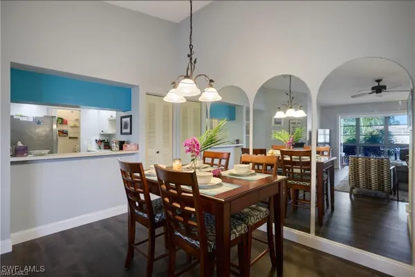 a view of a dining room and livingroom with furniture wooden floor a rug a potted plant and a chandelier