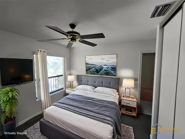 a bedroom with a bed a flat screen tv and a potted plant