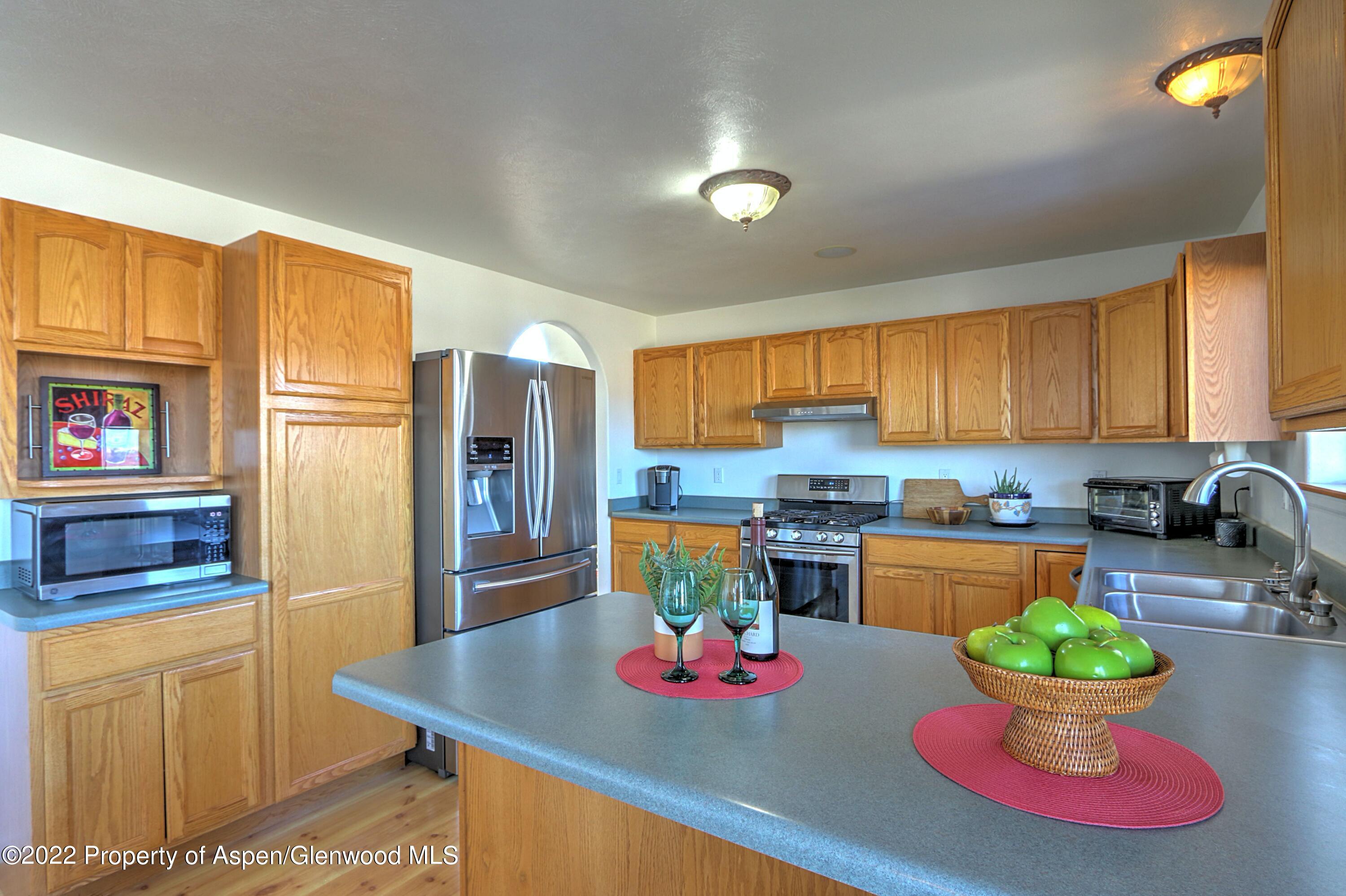 1220 Sage Court Rifle, CO 81650 - Photo 17 of 41 a kitchen with stainless steel appliances granite countertop a dining table cabinets and a refrigerator