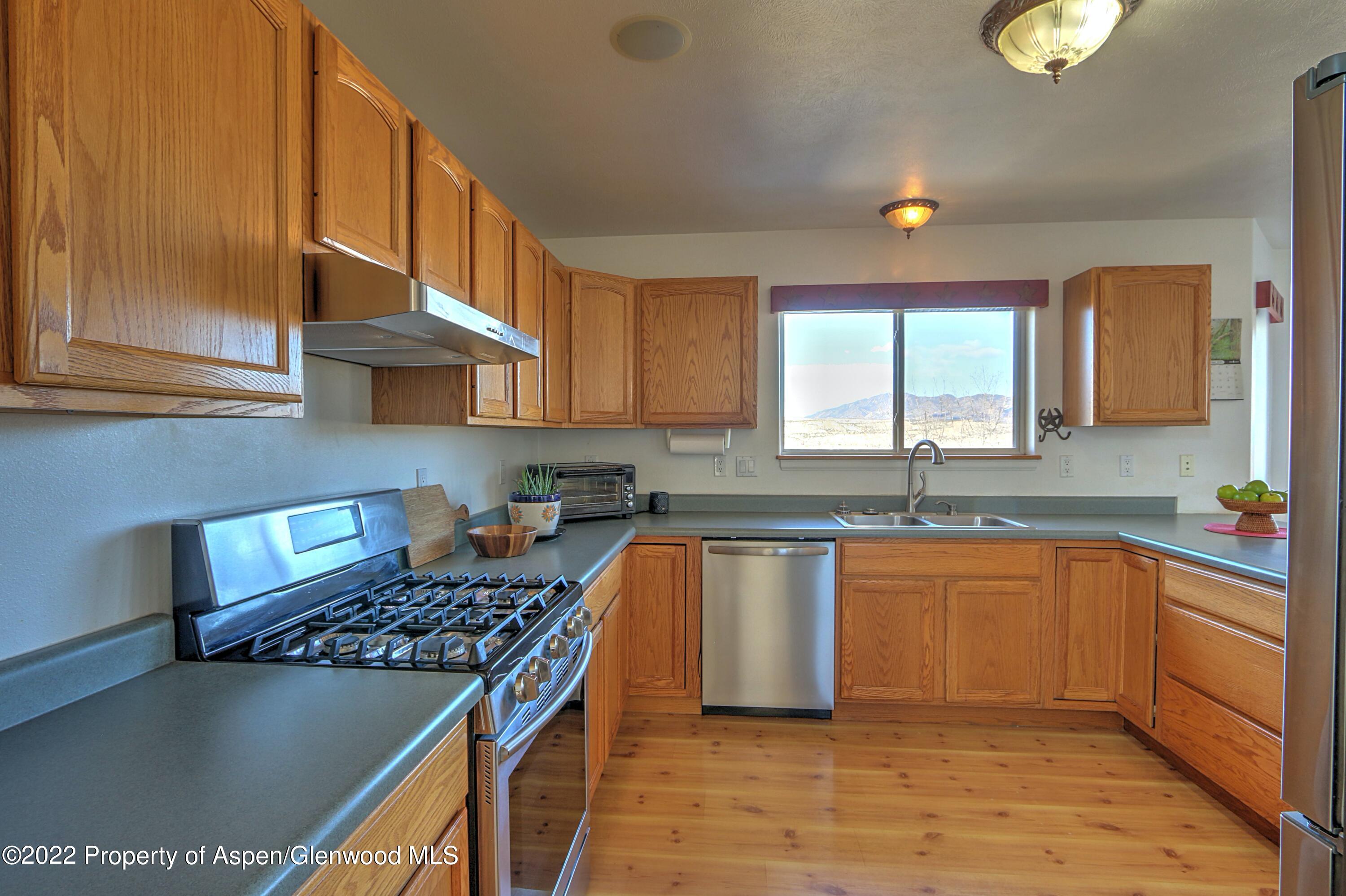1220 Sage Court Rifle, CO 81650 - Photo 18 of 41 a kitchen with stainless steel appliances granite countertop a stove a sink dishwasher and cabinets with wooden floor