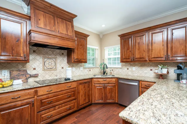 a kitchen with stainless steel appliances granite countertop a sink dishwasher stove and cabinets with wooden floor