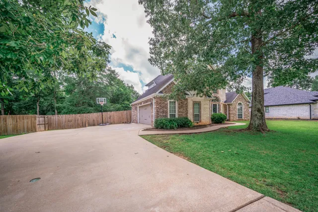 a view of a house with a yard and large trees