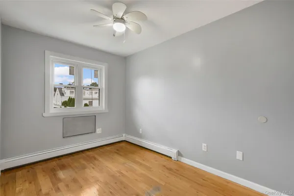 an empty room with a window and ceiling fan