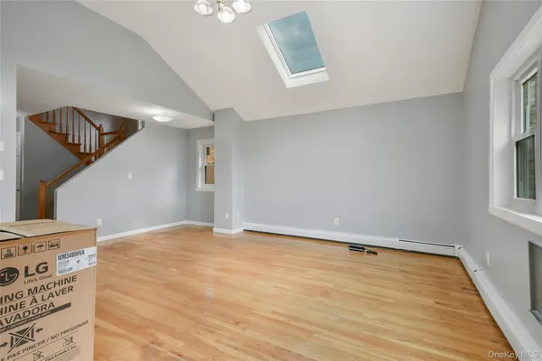 a view of an empty room with window and wooden floor
