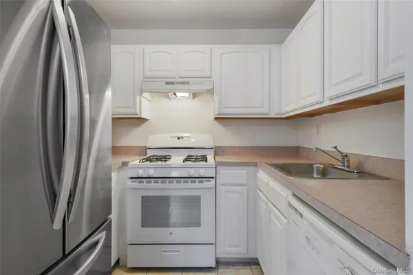 a kitchen with white cabinets and a stainless steel refrigerator stove