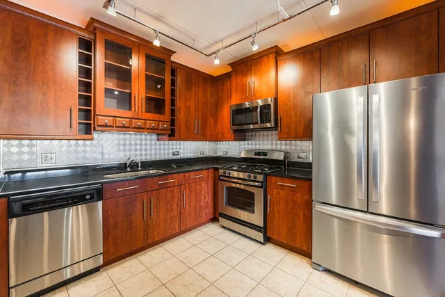 a kitchen with stainless steel appliances granite countertop a refrigerator a stove and a sink