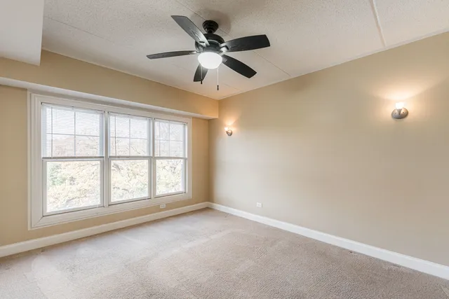 an empty room with ceiling fan and windows