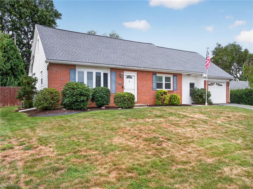 A classic brick and siding ranch offers a welcoming facade with blue shutters and an attached garage.