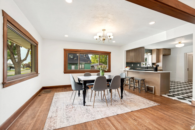 4883 South Center Street Murray, UT 84107 - Photo 3 of 32 Dining area featuring wood-finish flooring, two large windows with wood trim, recessed lighting, and a chandelier