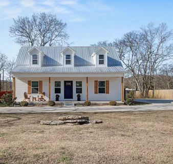 a front view of a house with garden and trees