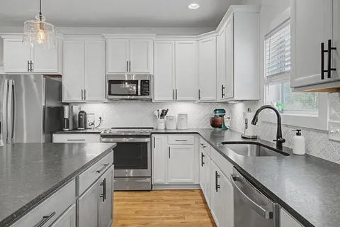 a kitchen with stainless steel appliances granite countertop a sink a stove a refrigerator and cabinets