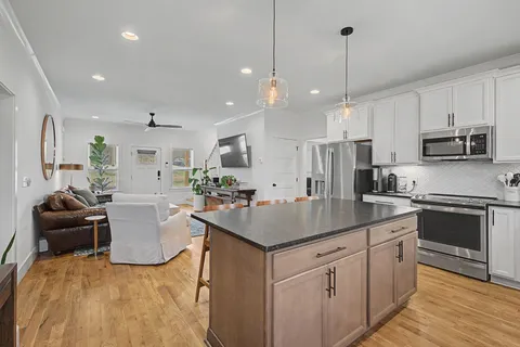 a kitchen with kitchen island granite countertop a sink counter top space appliances and cabinets