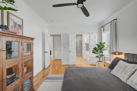 a spacious bedroom with a bed and a potted plant on the dresser