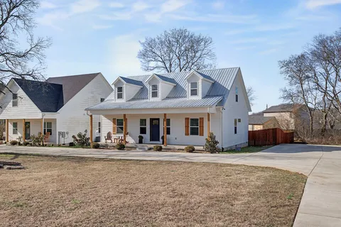 a front view of a building with small garden and trees