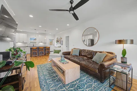 a living room with furniture kitchen view and a chandelier