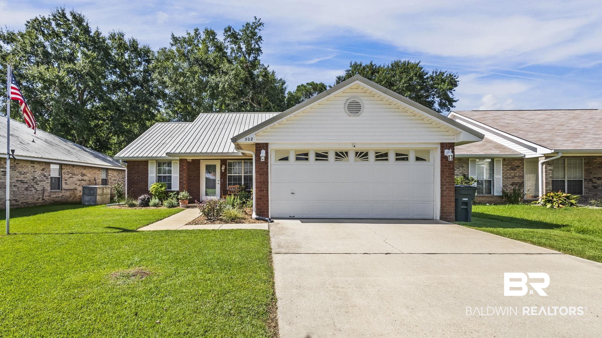 302 Cluster Street Foley, AL 36535 - Photo 2 of 28 Single story home with an attached garage, brick siding, driveway, a front lawn, and a metal roof