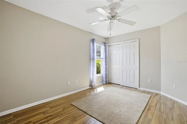 an empty room with wooden floor and ceiling fan