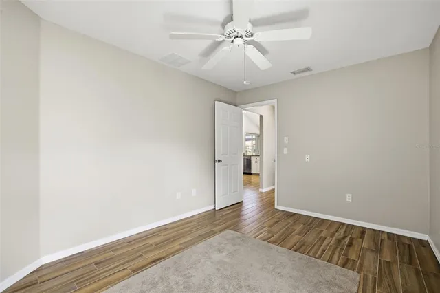 an empty room with wooden floor closet and windows