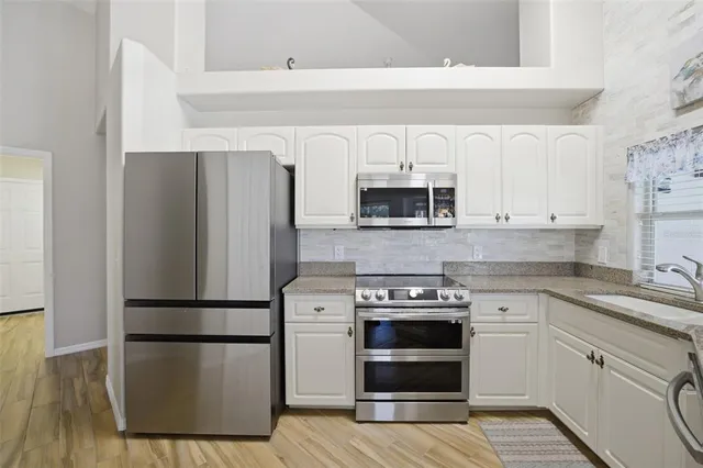 a kitchen with stainless steel appliances granite countertop hardwood floor sink stove dining table and chairs
