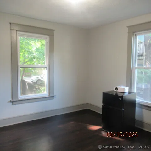 an empty room with wooden floor and window