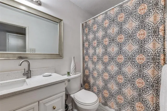 a bathroom with a granite countertop toilet sink mirror and shower