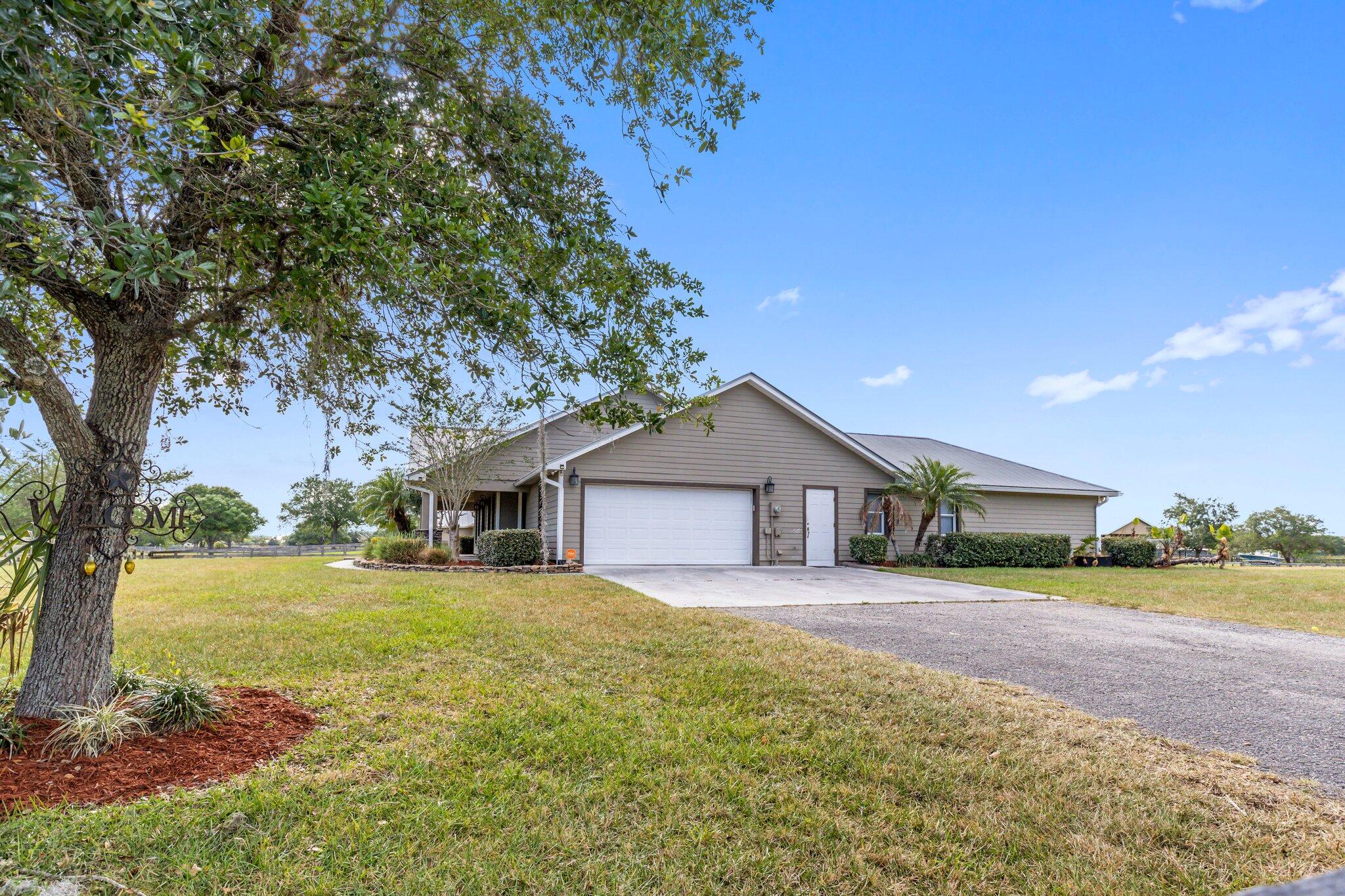 9850 Muller Road Fort Pierce, FL 34945 - Photo 49 of 52 a front view of a house with a garden and trees