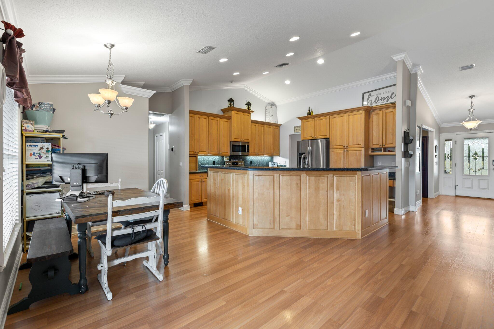 9850 Muller Road Fort Pierce, FL 34945 - Photo 10 of 52 a kitchen with stainless steel appliances kitchen island granite countertop a table chairs and a refrigerator