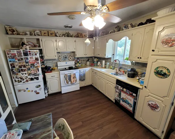 a kitchen with stainless steel appliances a stove a sink and white cabinets with wooden floor