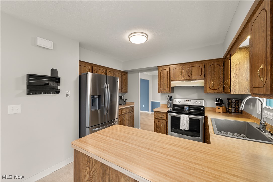 580 Orchardview Road Independence, OH 44131 - Photo 16 of 44 Kitchen with under cabinet range hood, appliances with stainless steel finishes, light countertops, and a sink