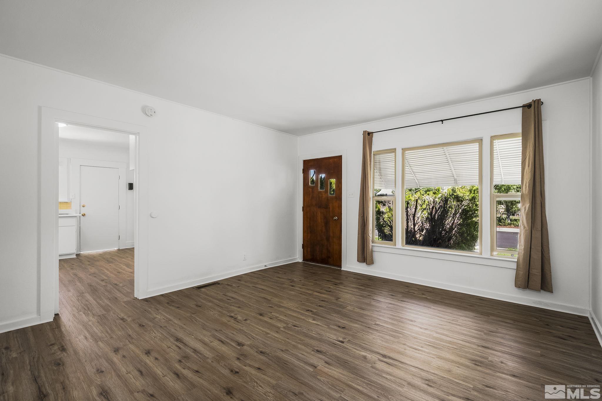 971 Lester Avenue Reno, NV 89502 - Photo 3 of 15 a view of an empty room with wooden floor and a window