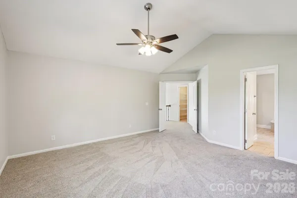 a view of an empty room and chandelier fan