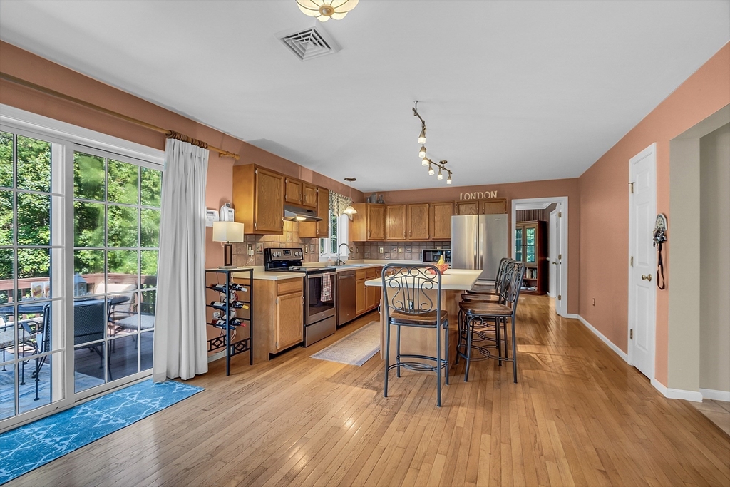 34 Pingry Way Ayer, MA 01432 - Photo 4 of 29 a kitchen with stainless steel appliances granite countertop a stove top oven a sink dishwasher a dining table and chairs with wooden floor