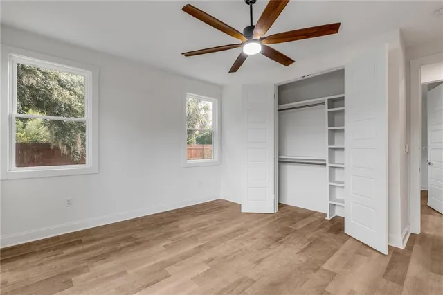 a view of empty room with wooden floor and fan