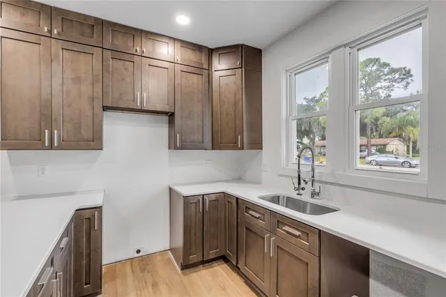 a kitchen with stainless steel appliances granite countertop a sink a window and a refrigerator