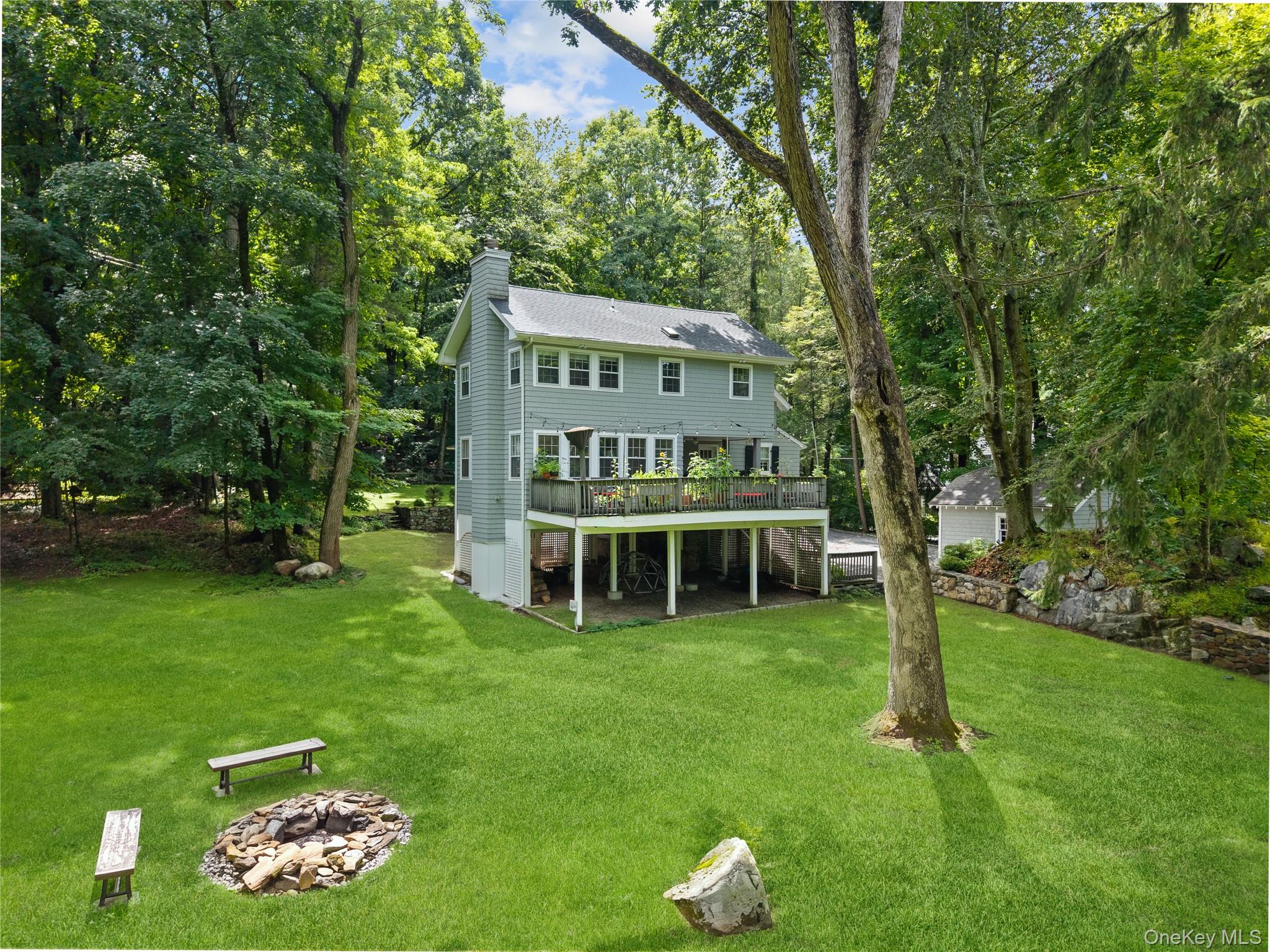 Expansive green lawn surrounded by mature trees, protected by green space and featuring a raised deck.