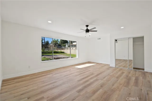 a view of empty room with wooden floor and fan