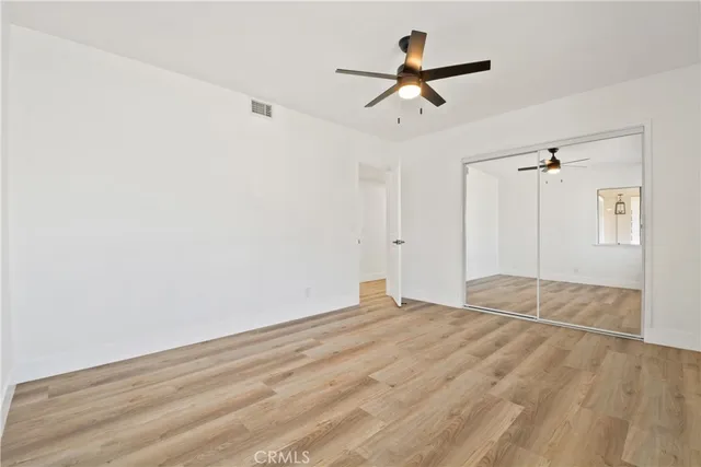 a view of empty room with wooden floor and ceiling fan