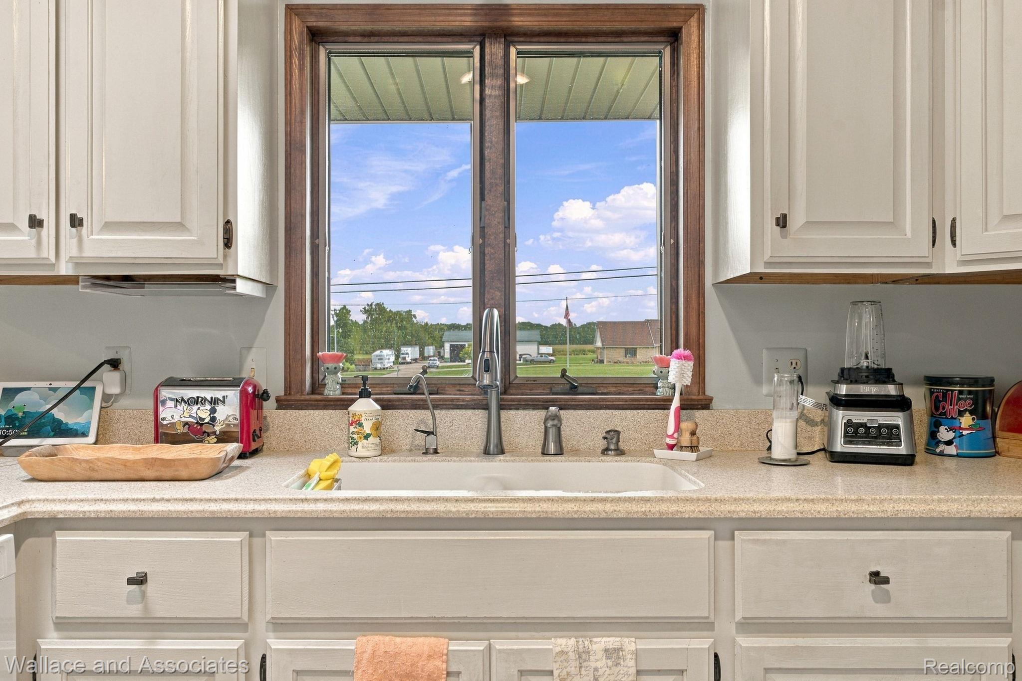 17076 27 Mile Road Ray, MI 48096 - Photo 17 of 63 White shaker-style cabinetry, light-toned countertops, and a double window with wood-finish trim