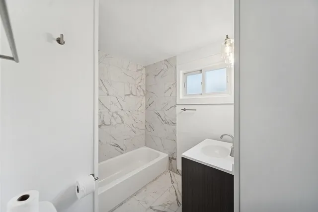 a bathroom with a granite countertop sink a toilet and bathtub
