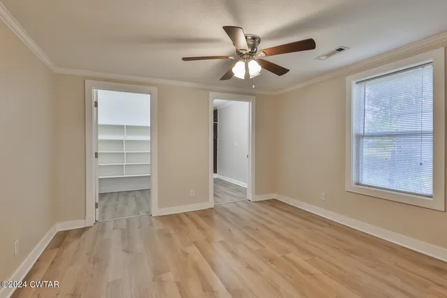 a view of an empty room with a window and wooden floor