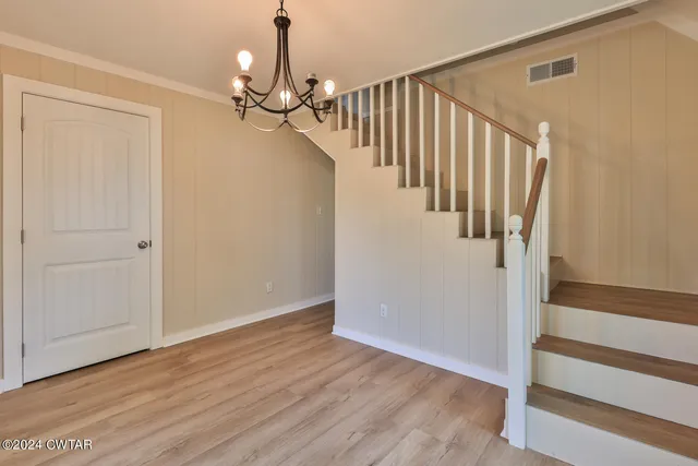 a view of a hallway with wooden floor and staircase