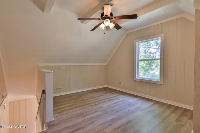an empty room with wooden floor fan and windows