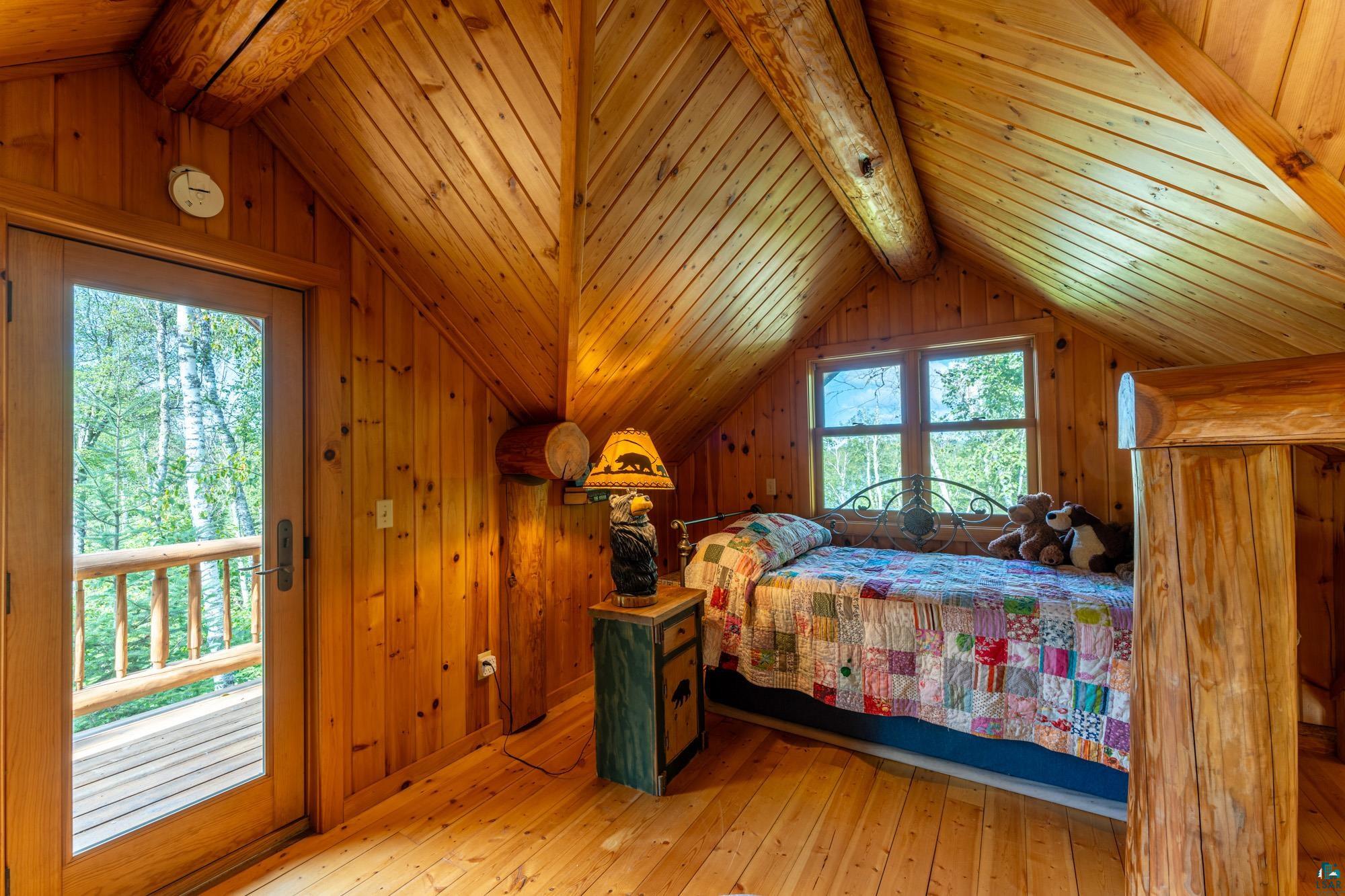 1911 Grouse Ridge Road Ely, MN 55731 - Photo 13 of 42 Bedroom featuring lofted ceiling with beams, wood walls, and light hardwood / wood-style flooring