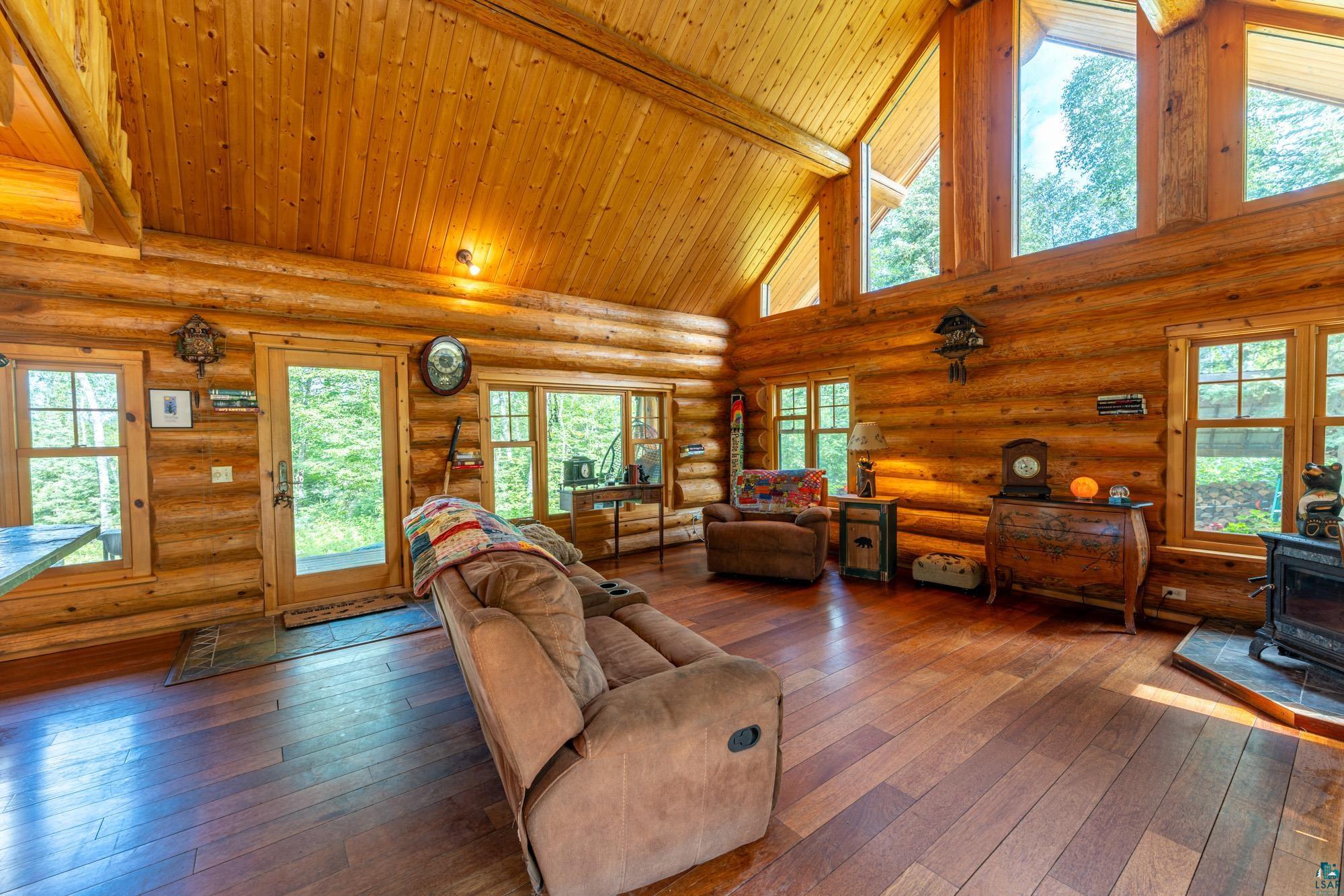 1911 Grouse Ridge Road Ely, MN 55731 - Photo 4 of 42 Living room featuring log walls, dark hardwood / wood-style flooring, high vaulted ceiling, and a wood stove