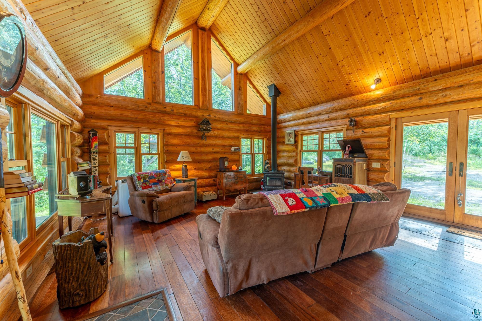 1911 Grouse Ridge Road Ely, MN 55731 - Photo 5 of 42 Living room with log walls, high vaulted ceiling, and a wood stove