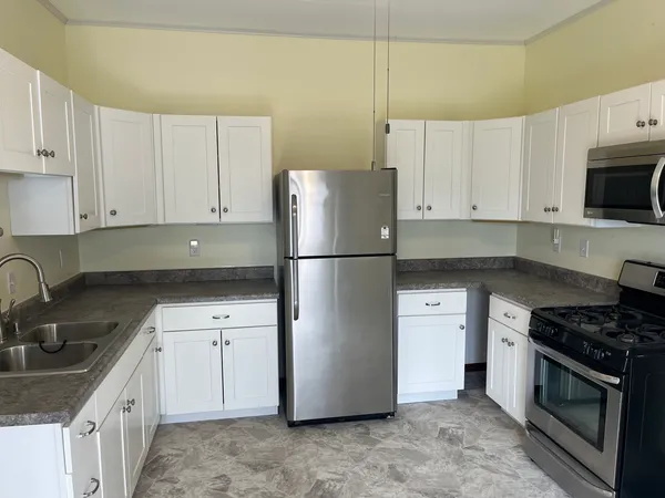 a kitchen with stainless steel appliances granite countertop a refrigerator a sink a stove a microwave and cabinets